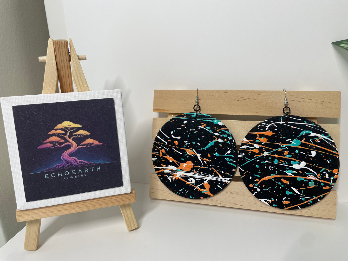 Earring display with abstract patterned earrings and a small canvas with 'Echoearth' branding.