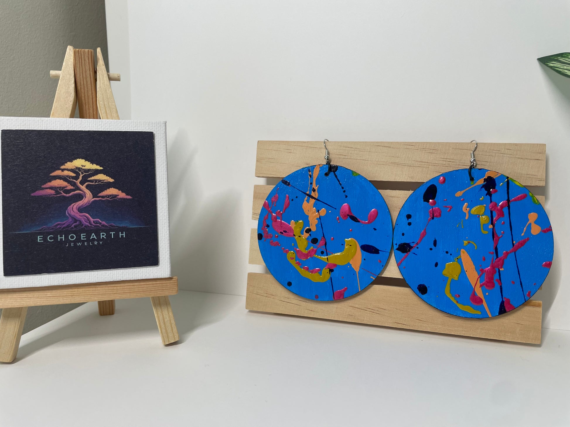 Colorful circular earrings on a wooden stand with Echo Earth Jewelry branding.
