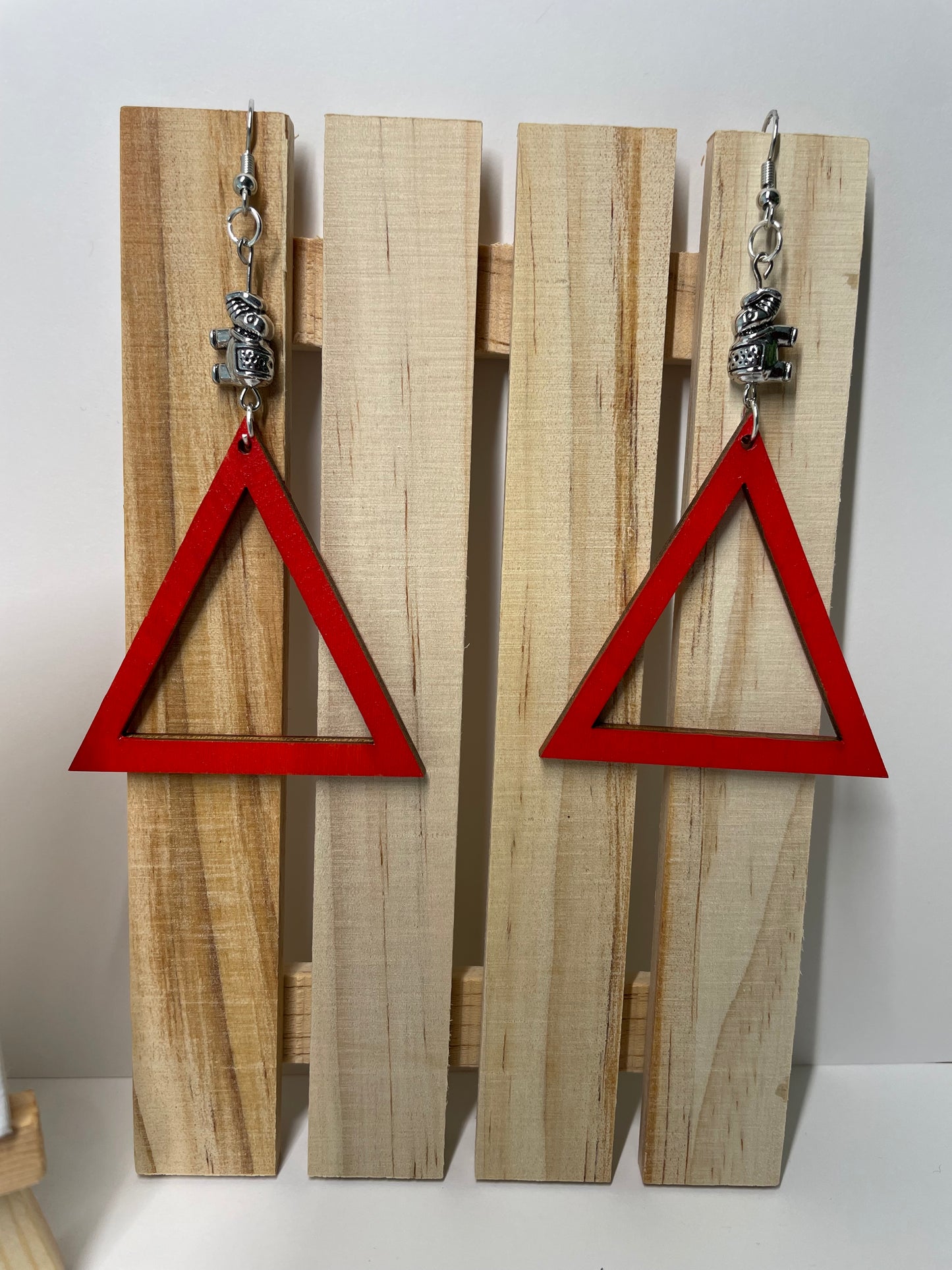 Wooden wall art with red triangles and metal elephants charms.